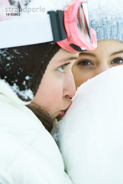 Teenager Mädchen küsst Schneeball  Nahaufnahme  Freund im Hintergrund