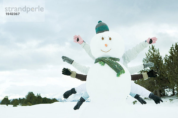 Junge Freunde verstecken sich hinter Schneemann  Arme ausgestreckt