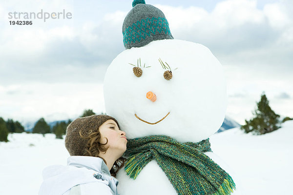 Mädchen an Schneemann gelehnt  wegschauend  Portrait