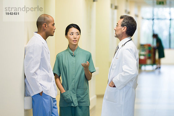 Medizinisches Personal im Flur stehend  diskutierend  einander anschauend