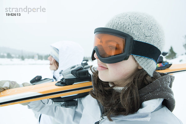 Zwei junge Skifahrer mit Ski auf der Schulter  wegschauen  Nahaufnahme