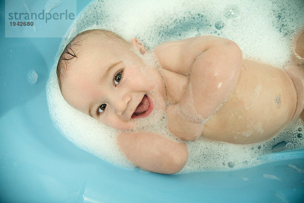 Nacktes Baby in der Badewanne  lächelnd vor der Kamera