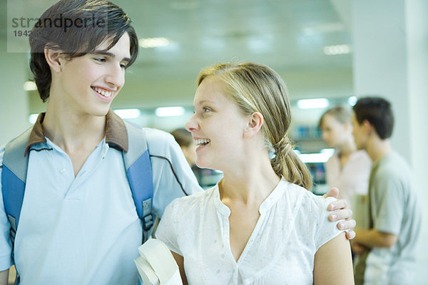 Zwei Schüler stehen zusammen  lächeln sich an  der eine Arm um die Schulter des anderen.
