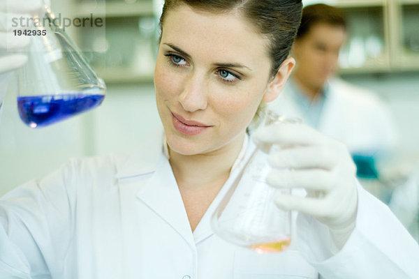 Junge Frau arbeitet im wissenschaftlichen Labor  hält Flaschen hoch