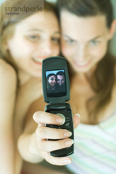 Teenager-Mädchen fotografiert sich selbst mit einem Freund mit dem Handy.