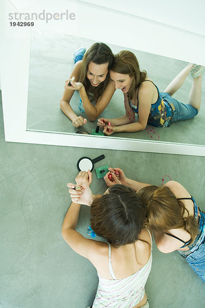 Zwei junge Freunde auf dem Boden liegend  sich selbst im Spiegel betrachtend  Blick von oben