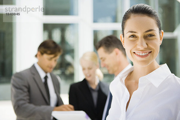 Junge Geschäftsfrau lächelt  Mitarbeiter sprechen über Vertrag im Hintergrund