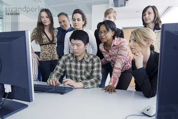 Junge Männer und jungen Frauen Blick auf Computer im Klassenzimmer