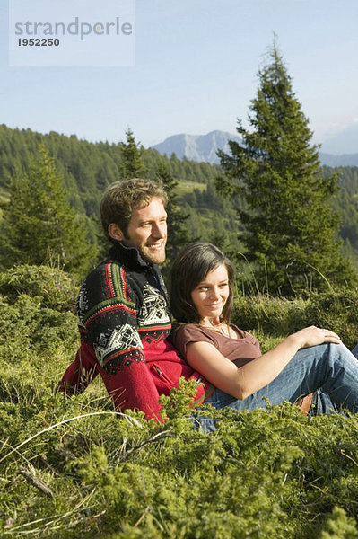 Junges Paar in den Bergen sitzend