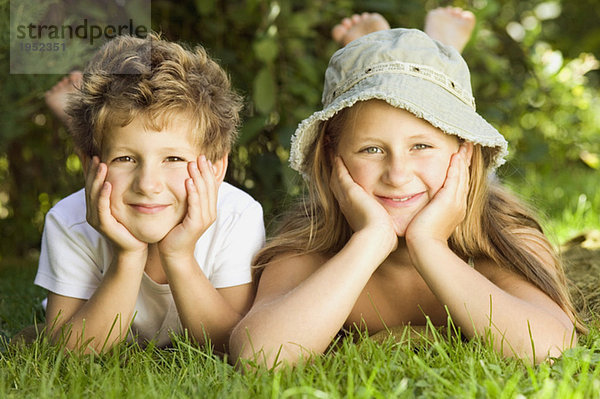 Junge und Mädchen (6-9) auf Gras liegend  Portrait