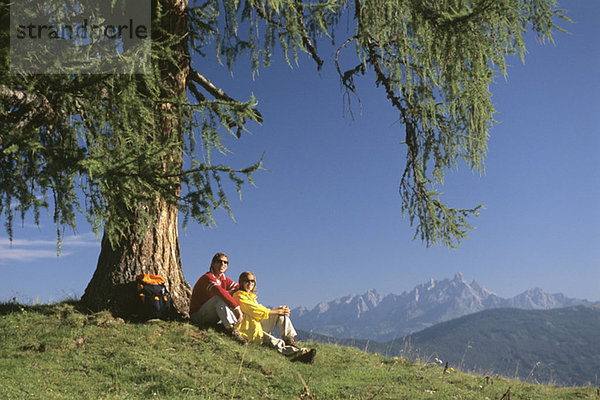 Paar mit Pause unter dem Baum in den Bergen