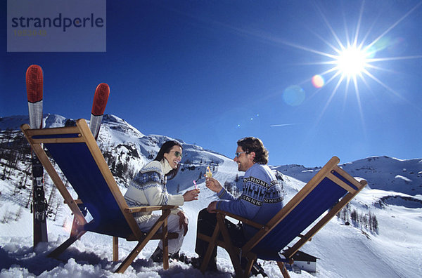 Paar sitzend auf Liegestuhl in Schneerösterbrille  Seitenansicht