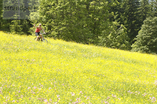 Junge Frau Mountainbiken im Feld