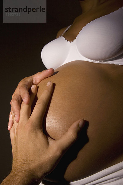 Schwangere Frau  Hände am Bauch  Mittelteil