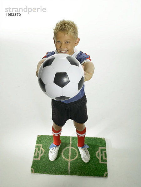 Junge (8-11) hält Fußball auf dem Spielfeld