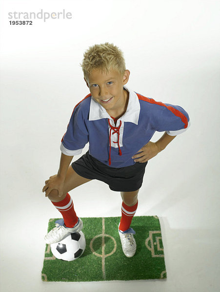 Junge (8-11) mit Fuß auf Fußball  Hand auf Hüfte