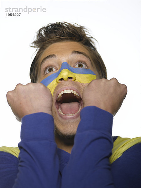 Junger Mann mit ukrainischer Flagge auf Gesicht  Mund offen  Blick nach oben  Nahaufnahme