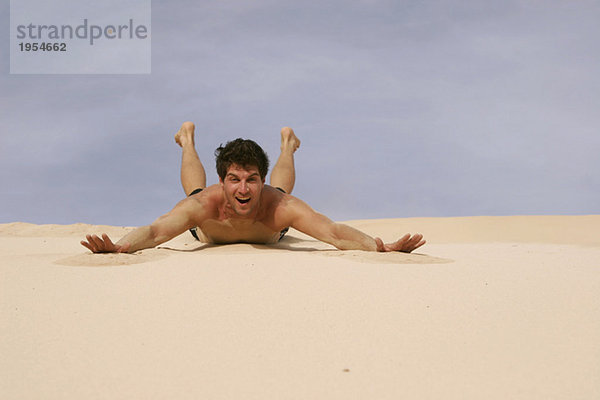 Mann gleitet auf Sand in der Wüste