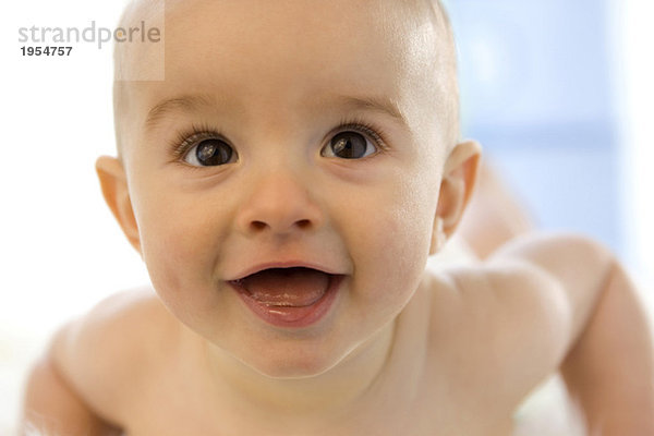 Junge (6-12 Monate) auf dem Bauch liegend  lächelnd