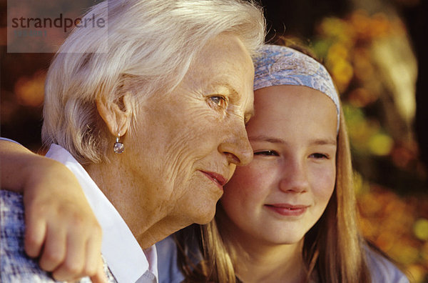 Enkelin und Großmutter mit den Armen herum  lächelnd