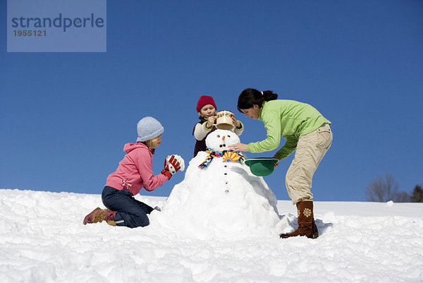 Österreich  Mädchen (6-17) beim Schneemannmachen  Tiefblick