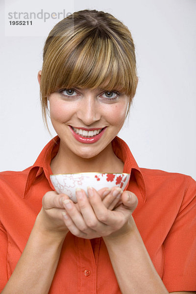 Junge Frau hält Teeschale  lächelnd  Portrait