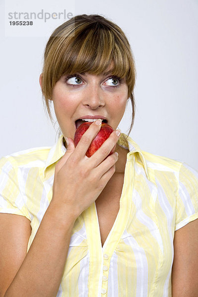 Junge Frau beißt Apfel  schaut hoch  Nahaufnahme
