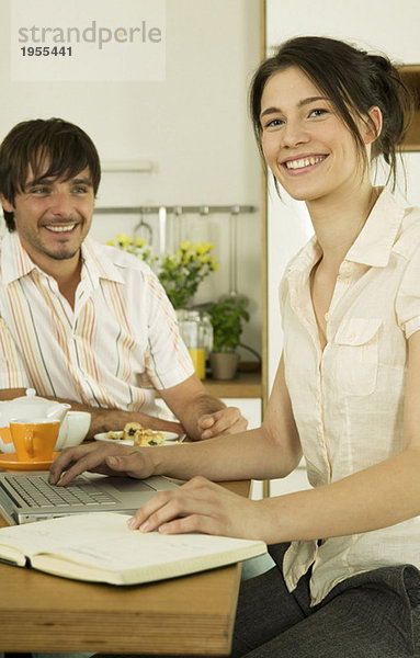 Junges Paar in der Küche  Frau mit Laptop  lächelnd