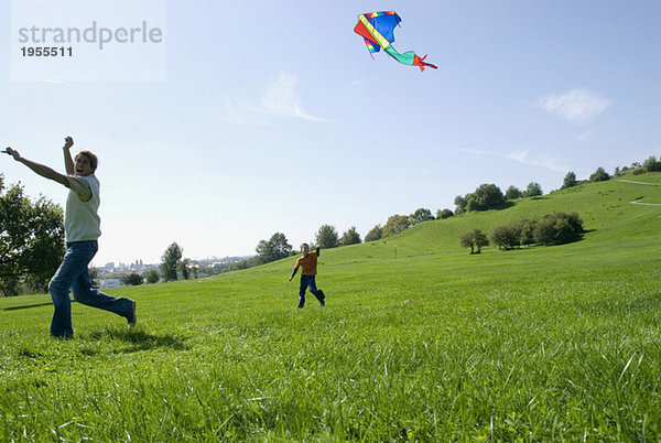 Vater und Sohn (4-7) beim Drachenfliegen im Park
