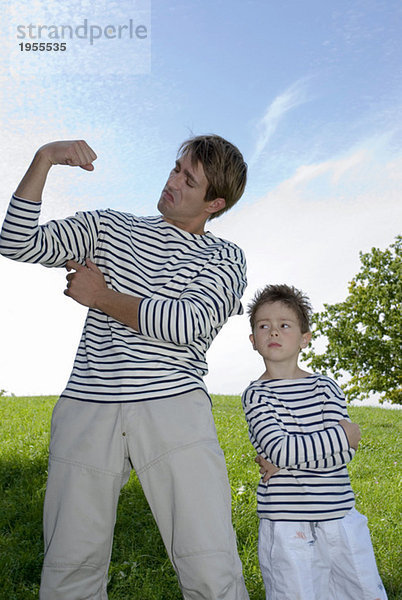 Vater und Sohn (4-7)  die Muskeln beugen  stehen im Park