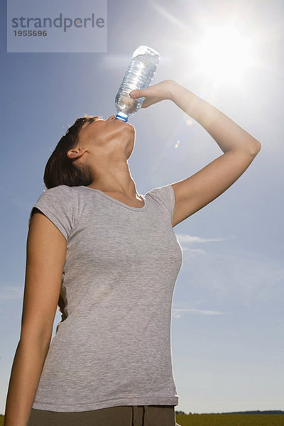 Junge Frau trinkt aus der Wasserflasche