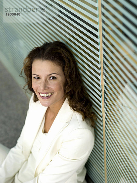 Geschäftsfrau auf dem Boden sitzend  lächelnd  erhöhte Ansicht  Portrait
