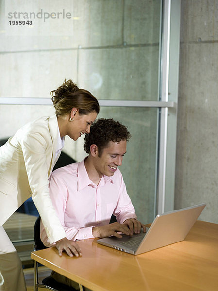 Mann und Frau im Büro  mit Laptop  lächelnd