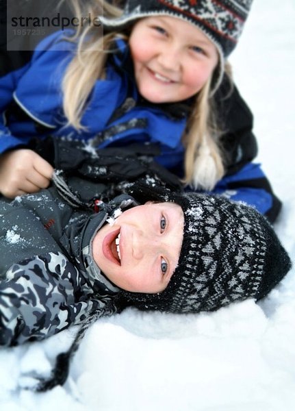 Mädchen und Junge tummeln sich im Schnee