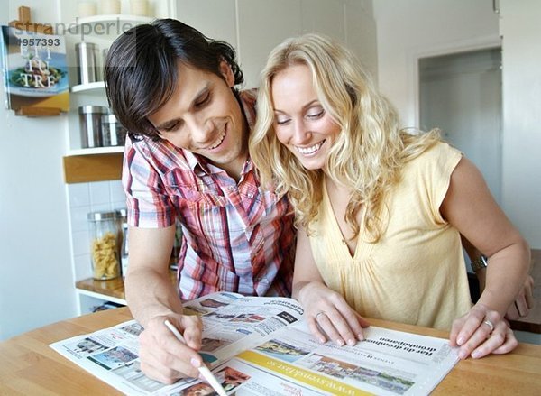 Guy und Girl beim Durchblättern von Immobilienanzeigen