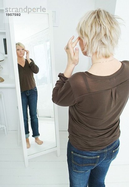 Frau schaut sich selbst im Spiegel an