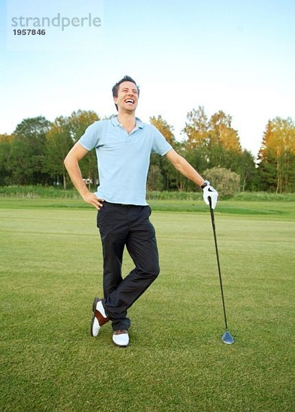 Mann lacht auf einem Golfplatz