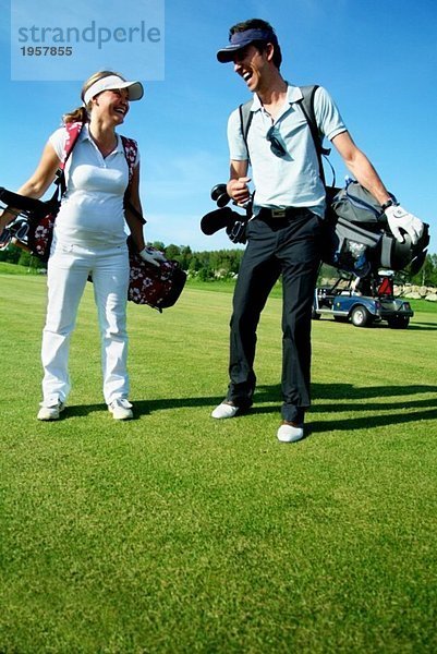 Zwei Leute  die auf dem Golfplatz rumhängen.