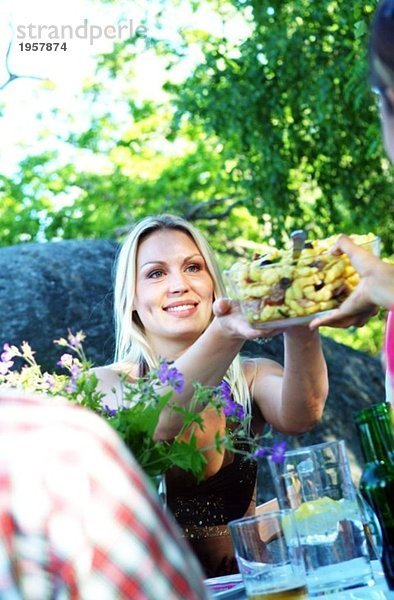 Junge Frau geht über Schüssel mit Salat