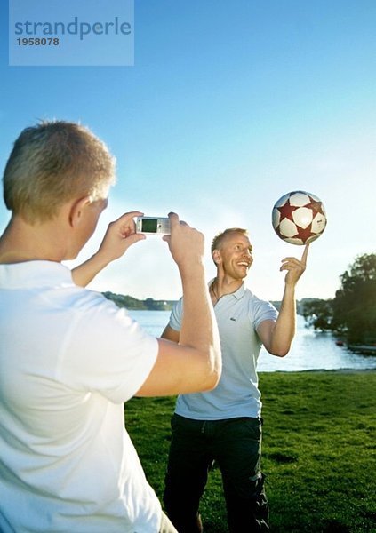 Der Typ macht ein Foto von einem Freund  der Fußball spielt.