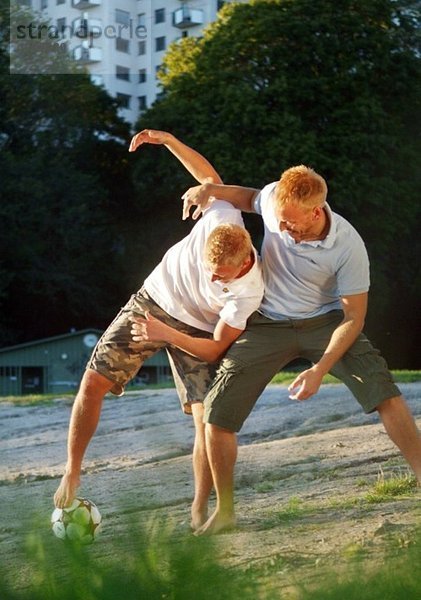 Zwei Jungs spielen Fußball im Park in der Innenstadt.