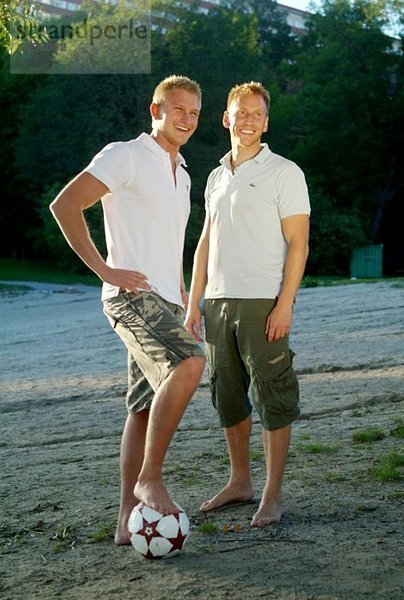 Zwei Typen mit einem Fußball am Strand.