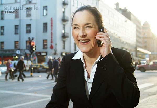 Enthusiastische Geschäftsfrau spricht auf ihrem Handy
