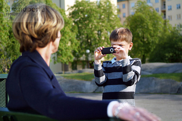 Junge fotografiert Großmutter mit der mobilen Kamera