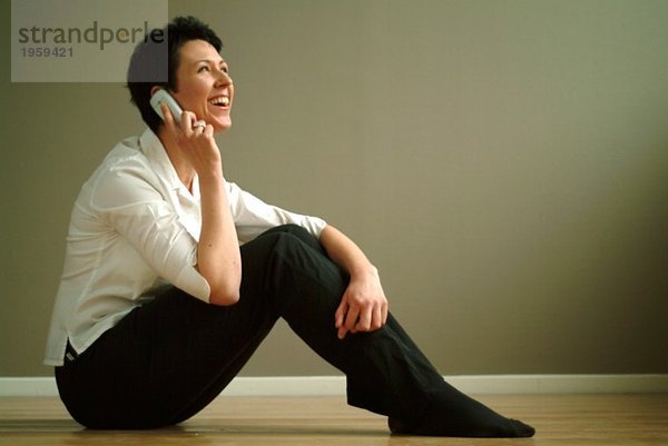 Frau auf dem Boden sitzend mit Telefon