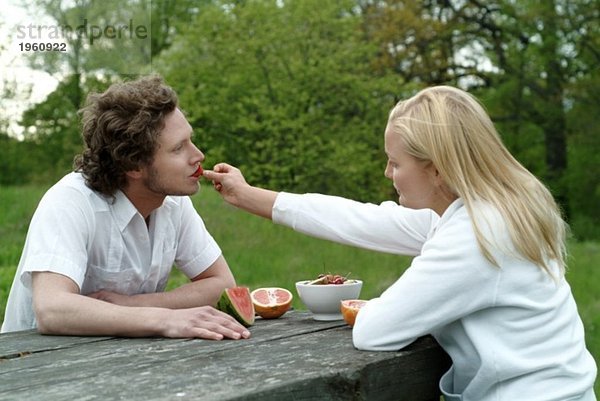 Mädchen füttert Junge mit Erdbeeren