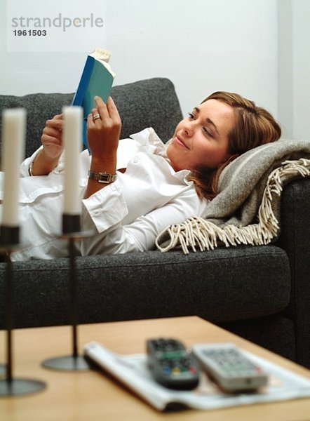 Junge Frau beim Lesen auf der Couch