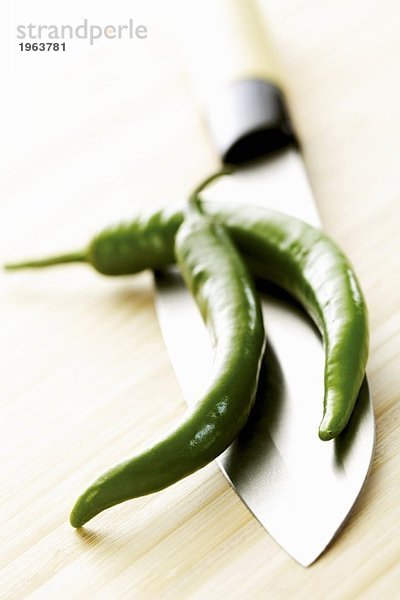 Zwei grüne Peperoni auf chinesischem Messer
