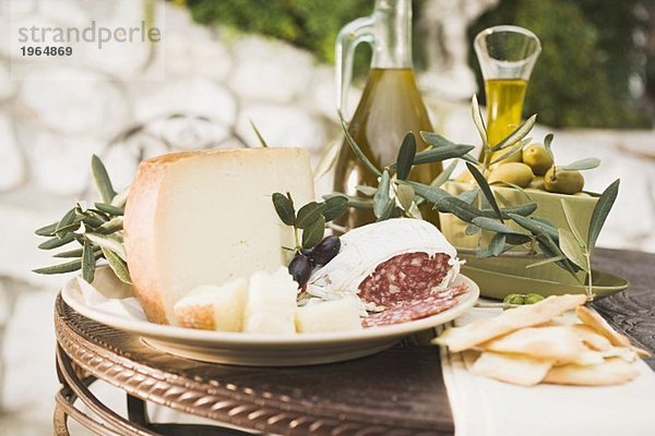 Käse  Salami  Oliven  Olivenöl  Cracker auf Tisch im Freien