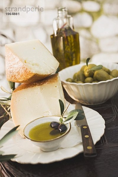 Käse  Oliven und Olivenöl auf Tisch im Freien